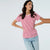 A woman modeling a red and white horizontally striped short-sleeve t-shirt with a white crew neck, paired with light blue jeans, against a solid light gray background.