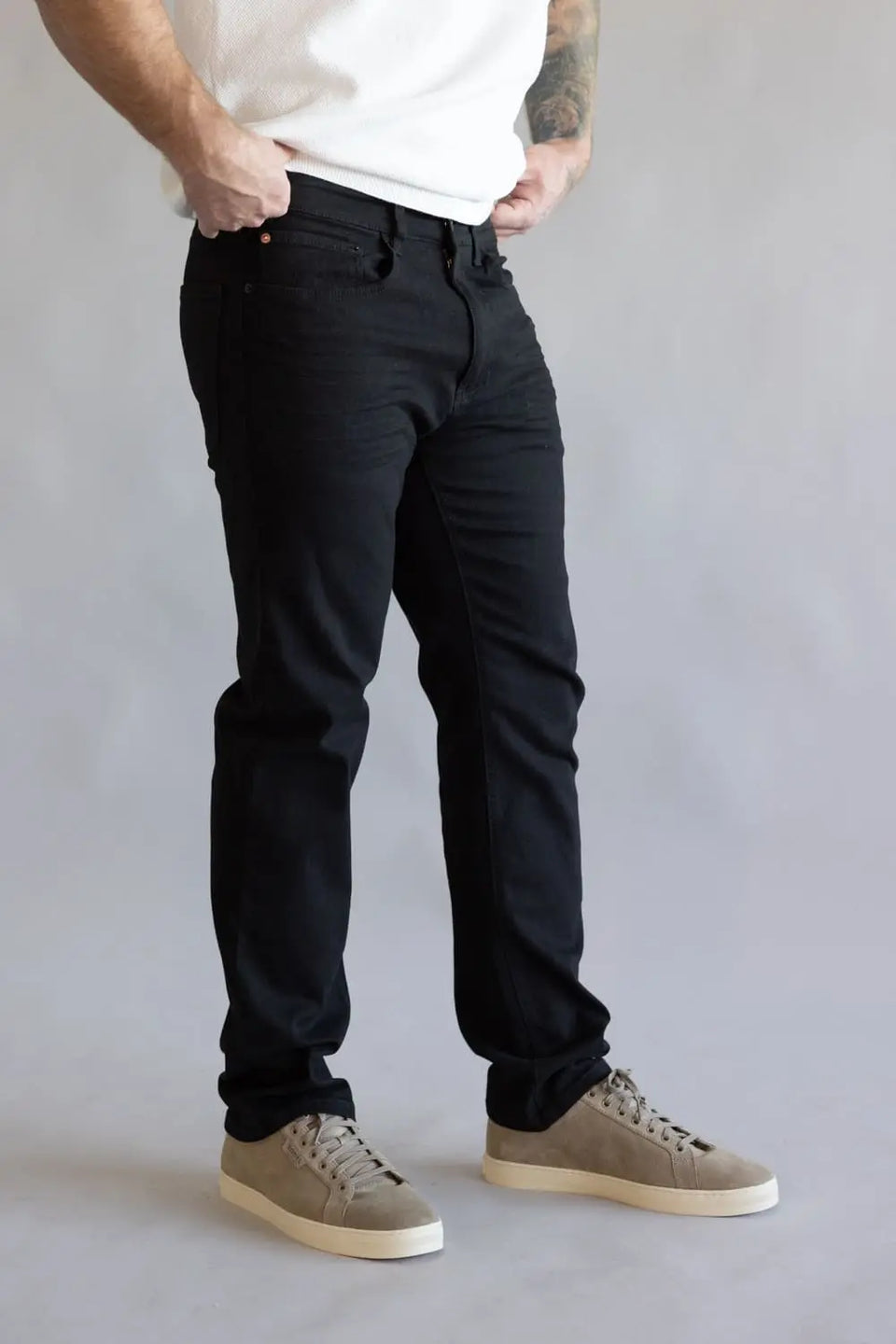 Person wearing black pants and beige shoes on a plain background
