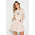 A woman modeling a light beige crewneck sweater and matching sequined flared skirt set against a plain white background.