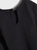 Close-up of a black long-sleeve shirt with a button on a white background