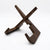 A dark brown wooden stand with a geometric, crossed design, photographed on a seamless white background.