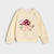 A cream-colored long-sleeve sweatshirt featuring a colorful graphic of a mushroom house, flowers, and a rabbit on the front, displayed against a light gray background.