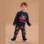 A toddler stands against a plain beige studio background wearing a navy long-sleeve Christmas-themed sweatshirt and matching patterned pants. The sweatshirt has a red truck carrying a green Christmas tree with the words 'We are NORTH PINE' in red.