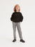 Child wearing a black sweatshirt and plaid pants on a white background