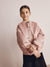 Young girl wearing a pink jacket against a plain background