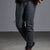 Dark gray jogger pants with zippered cargo pockets and elastic cuffs, shown on a model against a gray studio background.