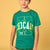 A boy wearing a green short-sleeve t-shirt with a yellow and white graphic on the front, standing against a solid yellow background.