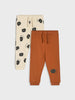 Two pairs of children's pants, one beige with black apple pattern and one brown, on a white background.