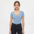 A woman modeling a light blue short-sleeve henley top with a buttoned V-neck, paired with black jeans, against a plain white studio background.