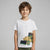 A young boy with brown hair wearing a white crewneck t-shirt with a graphic of a yellow and green bulldozer, standing against a solid gray studio background.