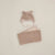 A soft fleece baby accessory set in a dusty blush pink color, featuring a bear-face aviator hat with ear flaps and a matching rectangular headband, laid out on a light beige background.