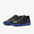 A pair of Nike soccer cleats in black with a vibrant blue sole and a subtle blue Swoosh logo, displayed on a clean light gray background.