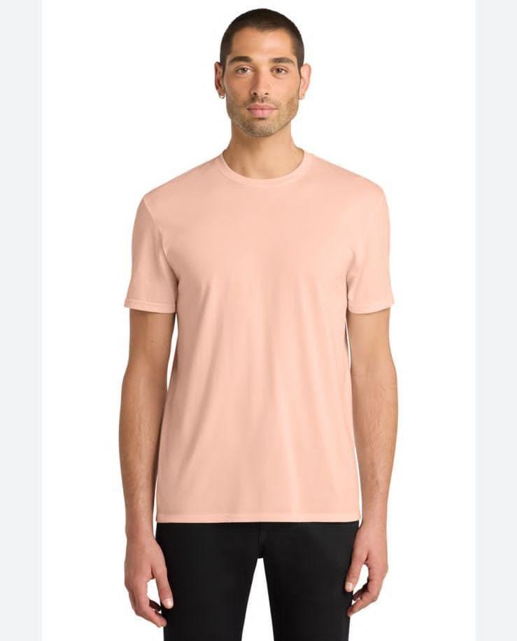 Man wearing a light pink t-shirt and black pants on a white background