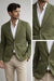 Man wearing a green blazer over a white shirt with beige pants on a light gray background.