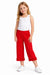 Young girl wearing a white top and red pants on a white background