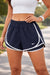 Person wearing navy athletic shorts with white trim and a Nike logo outdoors.