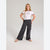 A young girl modeling a white ringer t-shirt with black trim and 'San Francisco' printed on the chest, paired with dark gray wide-leg cargo pants and pink slip-on shoes, against a light gray studio background.