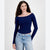 A woman modeling a navy blue ribbed long-sleeve top with a star motif on the chest, paired with light-wash blue jeans, against a plain light gray background.