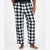 A person wearing black and white buffalo plaid lounge pants with a drawstring waist, shown from the waist down against a light gray studio background.