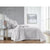 Neatly made bed with gray bedding in a bright bedroom.