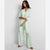 A woman modeling a light mint green two-piece lounge set consisting of a long-sleeve open-front cardigan and matching wide-leg pants, set against a plain light gray studio background.
