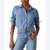 A woman wearing a light blue button-up shirt with thin white vertical stripes and rolled-up sleeves, paired with light-wash blue jeans, shown against a plain white background.