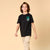 A child model wearing a black short-sleeve t-shirt with a teal and white graphic on the left chest that reads 'NEVER STOP RUNNING' with a running shoe illustration, paired with beige pants, against a solid beige background.