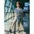 A young boy stands in a brightly lit airport terminal wearing a navy and white horizontally striped short-sleeve t-shirt, light gray shorts, white socks, and black and white sneakers.