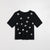 A black short-sleeve crewneck top featuring scattered white embroidered daisy-like floral motifs, displayed flat against a light gray background.