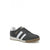 A dark gray suede low-top sneaker with three white stripes on the side, a white midsole, and a gum brown outsole. The brand name 'KOMFA' is printed in gold on the side of the shoe.