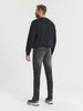Man wearing a black sweater and gray jeans on a white background