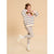 A young girl posing in a cream and navy blue striped knit sweater with pink lettering, paired with leopard print leggings and white sneakers, set against a solid beige background.
