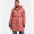 A woman wearing a dusty rose pink hooded puffer coat with black drawstrings and black zipper details, paired with blue jeans, against a plain white studio background.