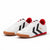 A pair of Hummel Corret low-top sneakers in white leather with black chevron stripes, red accents on the collar and midsole, and gum soles, shown on a white background.