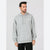A man wearing a light gray heather pullover hoodie with a small white rectangular patch on the left chest, paired with black pants, set against a plain light gray studio background.