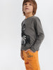 Child wearing a gray long-sleeve shirt with a black spider design and orange pants on a white background