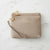 A taupe pebbled leather wristlet clutch with gold-tone hardware, featuring a wrist strap, a top zipper, and a horizontal card slot. The brand name 'LONDRENE COLLECTION' is embossed on the front, set against a white marble background.