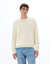 Man wearing a cream sweater and blue jeans on a white background