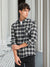 Person wearing a black and white plaid shirt standing against a neutral background