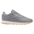 A Reebok Classic Leather sneaker in gray, featuring a white midsole and a gum brown outsole, shown from a side profile view on a white background.