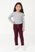 Young girl wearing a gray long-sleeve shirt and burgundy pants on a white background