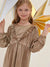 Young girl wearing a gold dress with ruffles against a white background