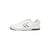A white low-top athletic sneaker shown from the side profile against a solid white background. The shoe features a white leather upper, white laces, a black and white chevron logo on the side, and a black outsole.