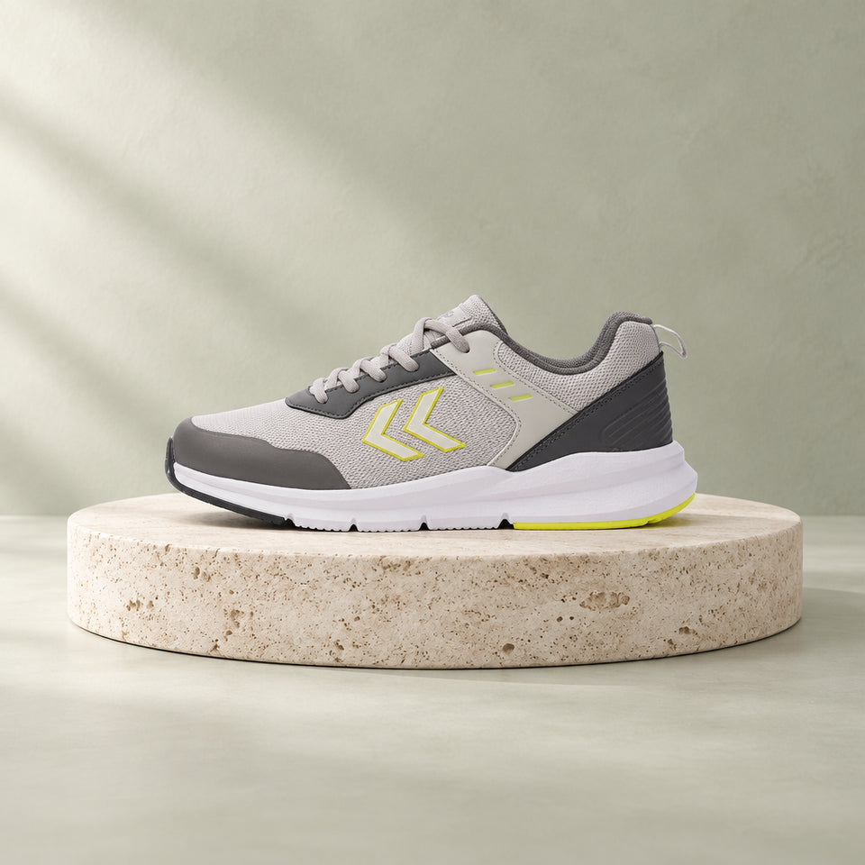 A light gray and dark gray athletic sneaker with bright yellow accents on the side logo and heel, shown in a side profile on a white background.