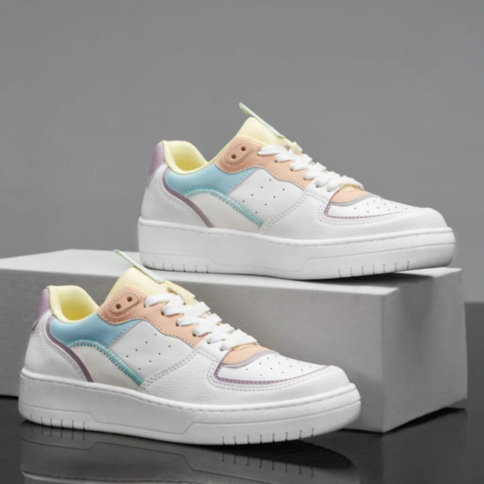 A pair of low-top platform sneakers in white with pastel accents in light blue, peach, yellow, and lavender, displayed on a gray box against a gray background.