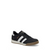A black low-top sneaker with three white side stripes, a white midsole, and a brown gum sole, shown on a plain white background.