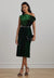 Woman wearing a green off-shoulder dress with a belt against a plain background