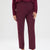 A model wearing a pair of high-waisted, straight-leg trousers in a deep burgundy color, paired with a matching long-sleeve top, against a plain light gray studio background.