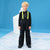 A young blonde boy wearing a black ski outfit with neon yellow-green suspenders, standing against a blue studio backdrop with a white snowflake-patterned floor.
