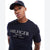 A man wearing a navy blue Tommy Hilfiger t-shirt and matching baseball cap, photographed against a clean white background.